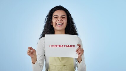 Happy, sign and face of woman in studio for employment, recruitment or hiring at job interview. Excited, smile and portrait of young female model from Colombia with hire me poster by blue background.