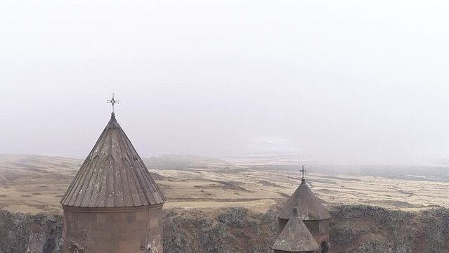Drone footage of Saghmosavank at the top of Kasagh gorge with dense fog in the background, Armenia