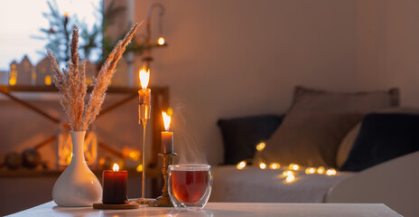 hot tea in thermo glass with christmas decor and burning candles at home - obrazy, fototapety, plakaty