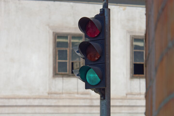 Selective focus photo of a red traffic light on a metal pole with an old house in the background