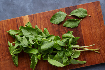 Top view of basil leaves on cutting board with blue-gray background