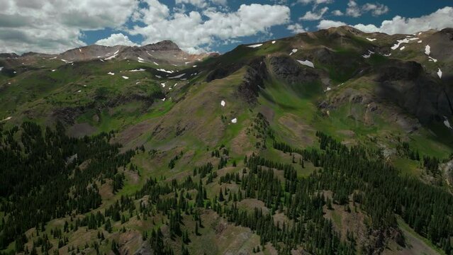 Aerial cinematic drone summer Million Dollar Highway Red Mountain Pass Silverton Ouray Telluride afternoon green lush wildflowers road high altitude scenic view Rocky Mountain 14er backward movement