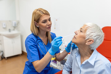 Fototapeta premium Doctor in a protective suit taking a throat and nasal swab from a patient to test for possible coronavirus infection