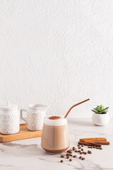 Chic large glass of freshly brewed coffee with foam and ground cinnamon on a marble table. still life. Vertical front view.