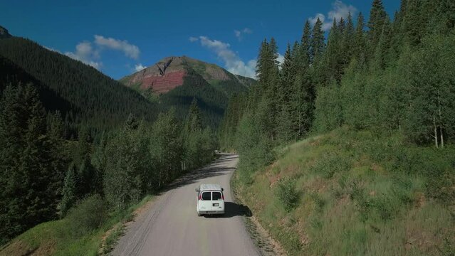 Aerial drone cinematic Ice Lake Basin trailhead driving van county road summer early morning Silverton Telluride Colorado Rocky Mountains Aspen forest 14er peaks forward follow motion