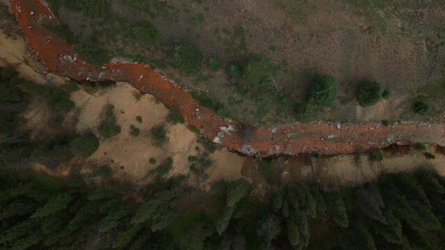 Aerial cinematic drone orange river Cement Creek summer high altitude Silverton Ski Area resort Telluride Prospect Gulch Colorado Rocky Mountains stunning drive looking down steam movement