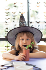 Children's Halloween party. A girl in a witch costume makes crafts for decorating a house on...