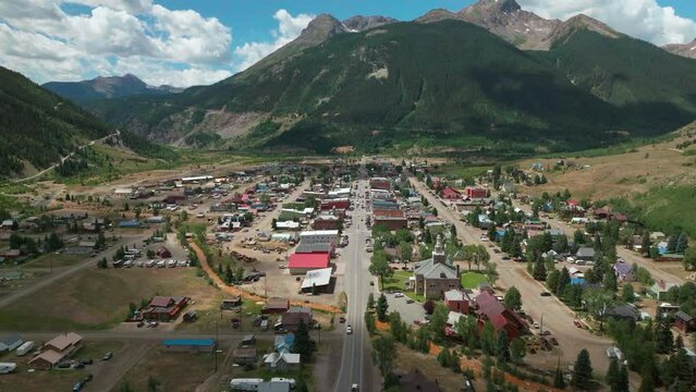 Aerial cinematic drone summer morning downtown Silverton Main Street southern Colorado stunning lush green blue sky partly cloudy Rocky Mountains town forward reveal movement
