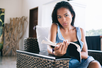Thoughtful female relaxing with novel in room