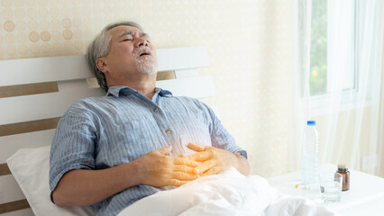 Senior male asian suffering from bad pain in his have a stomachache at home - senior healthcare...