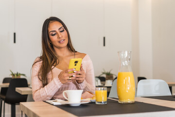 Businesswoman using phone while having breakfast in a luxury hotel