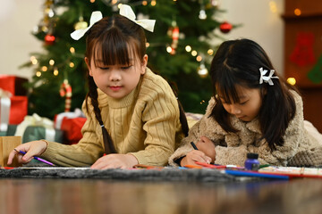 Happy little girls having fun making greeting card for New Year and Christmas at home