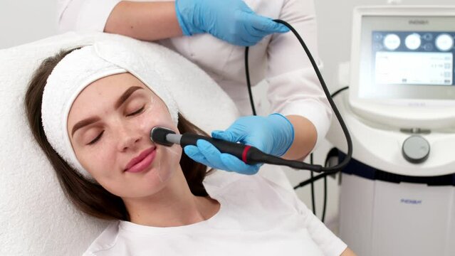 Close-up of a young woman's face during microcurrent therapy. Procedure for electrical stimulation of the face, rejuvenation, anti-wrinkle. The concept of youth and modern cosmetology technologies.