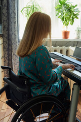 Rear view of disabled woman using wheelchair playing piano