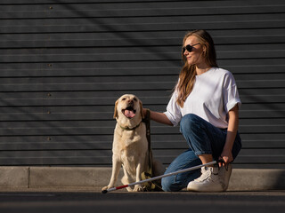 A blind woman walks her guide dog on the street. Girl hugging a labrador. 