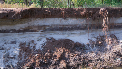 Coastline erosion, layered soil consisting of black soil and sand.