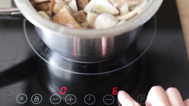 Turning off the induction cooker on which mushrooms are cooked. A modern metal pan on an induction cooker. Fresh wild mushrooms are boiled in a saucepan.