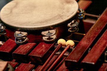 tambourine and drumsticks lie on a wooden xylophone