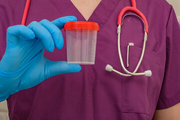 Lekarz trzyma pusty pojemnik na mocz w dłoniach 