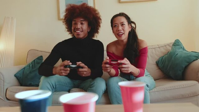 Young couple with gamepads playing video game at home