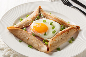 Galette complete Breton buckwheat pancake with egg cheese and ham closeup on the plate on the...