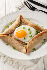 Homemade buckwheat crepe galette with egg, ham and green onion closeup on the plate on the table....