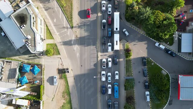 Aerial drone high angle footage of rush hour traffic on a summer morning in eastern Europe. Tracking top down shot of private and public transportation full of commuters. 4k helicopter video.
