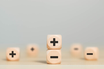 Wooden blocks showing plus and minus signs. The concept of opposites. Decision making. Positive or...