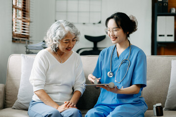 Obraz premium Asian caregiver doctor examine older patient use blood pressure gauge. woman therapist nurse at nursing home taking care of senior elderly woman sit on sofa.Medical service concept.