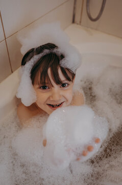 Boy playing with soap sud in bathtub at home