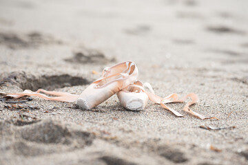 Pointe shoes for ballet. Pointe shoes lie on the sand. Ballet shoes.