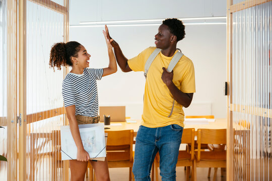 Students giving high-five to each other in doorway at university