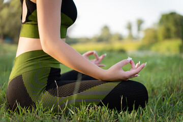 Close-up of a girl in asana, lotus position. the atmosphere of practicing yoga in nature as part of retreats and festivals.