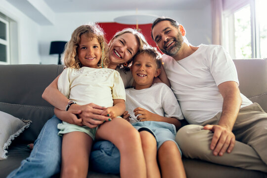 Happy parents with children sitting on sofa at home