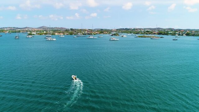 Small inflatable skiff boat cross Spanish Waters of Curacao against current, aerial panoramic