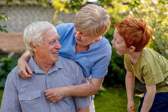 Grandson near grandmother with arm around senior man in garden