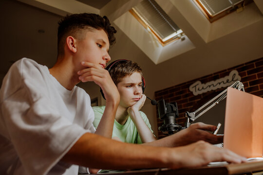 Teenage friends podcasting in front of laptop at home