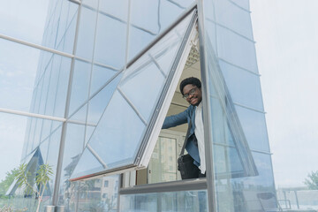 Smiling businessman opening window of office building
