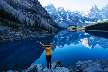 Tourists wearing yellow winter coats stand on the top of the mountain, raising their hands, feeling...
