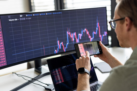 Businessman examining graph on mobile phone in office