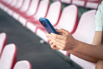 Close-up, woman uses a smartphone while sitting in the stadium stands.