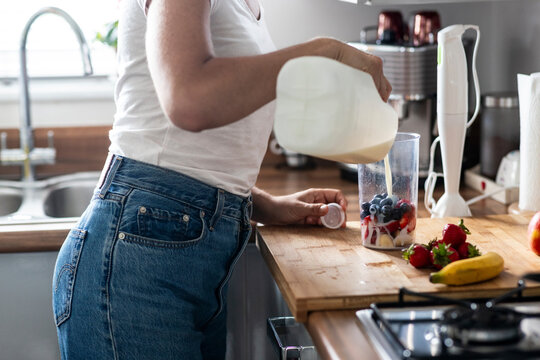 Woman preparing healthy milkshake in kitchen at home