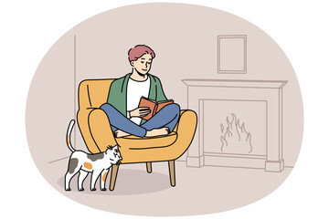 Happy young man sit in chair at home near fireplace reading book. Smiling guy relax in armchair enjoying literature. Hygge and domestic weekend. Vector illustration.
