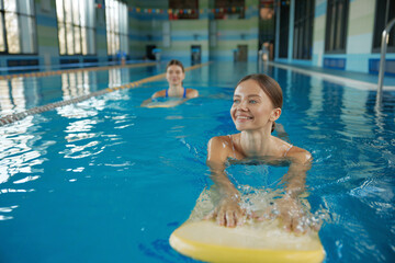 Young women exercising with swimming board at pool