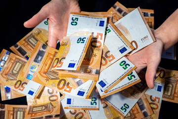 Financial success with hands presenting 50 Euro banknotes above a generous pile, symbolizing wealth, prosperity or financial management, against black backdrop, representation of abundance or opulence - obrazy, fototapety, plakaty