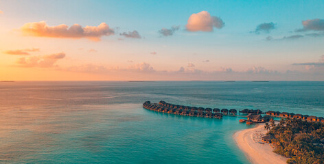 Aerial sunset panoramic landscape luxury tropical resort water villas. Beautiful island beach...