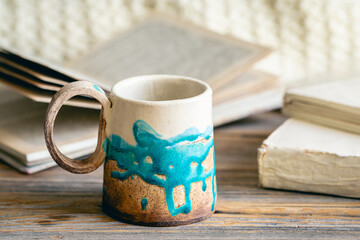 Handmade cup and books close-up on a wooden surface.