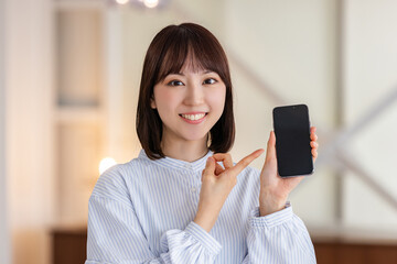 スマホを指差す笑顔のビジネスウーマン