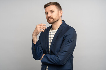 Charismatic serious relaxed unshaved man isolated on grey studio background with hands crossed on chest. Stylish man looks like manager, businessman, entrepreneur, freelancer, employee, executive