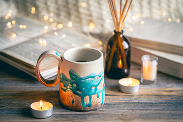 Cozy composition with a cup on a blurred background with books and bokeh lights.